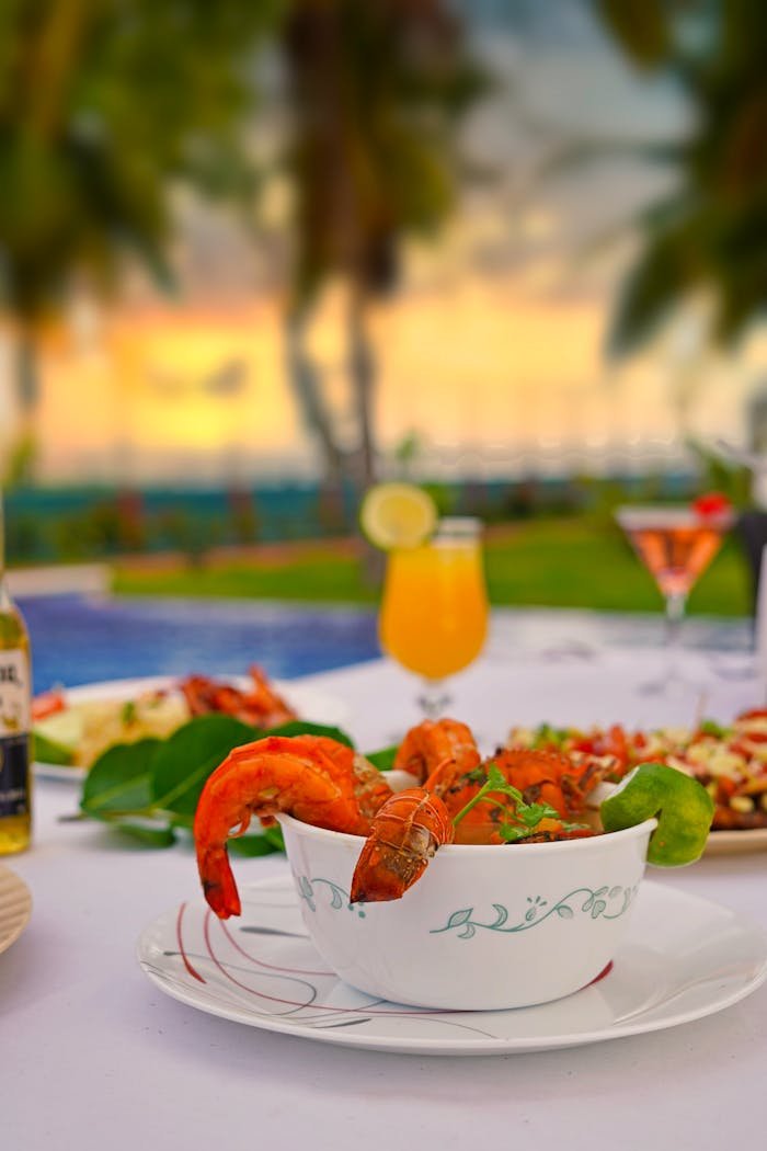 A vibrant seafood dinner featuring shrimp, set by the beach during a stunning sunset, capturing a tropical vibe.