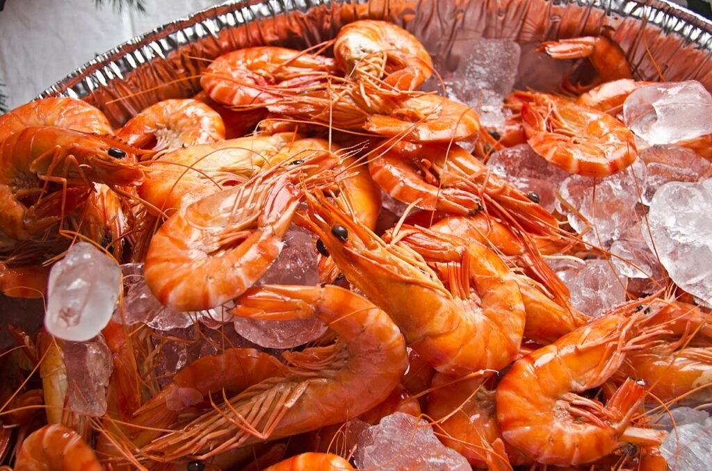 pexels photo 6372957 A vibrant display of fresh orange shrimps on a bed of crushed ice, perfect for a seafood feast.
