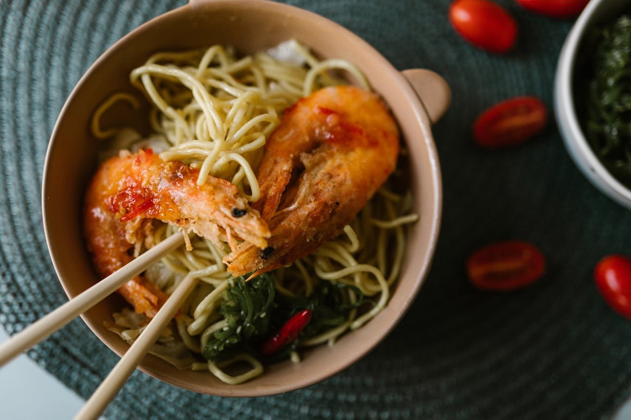 Top view of a flavorful shrimp noodle bowl with fresh vegetables, perfect for Asian cuisine lovers.