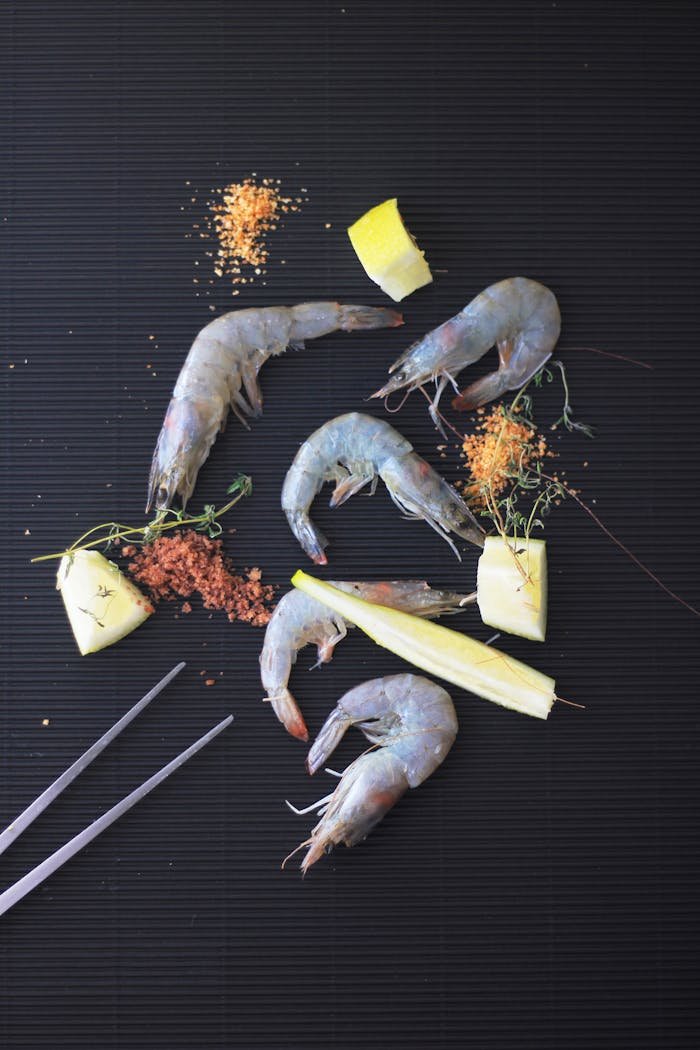Overhead view of raw shrimps with lemongrass and spices on a dark background, ideal for food blogs.